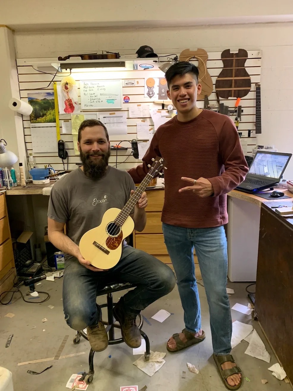 Micah and Aina in the workshop with a finished ukulele