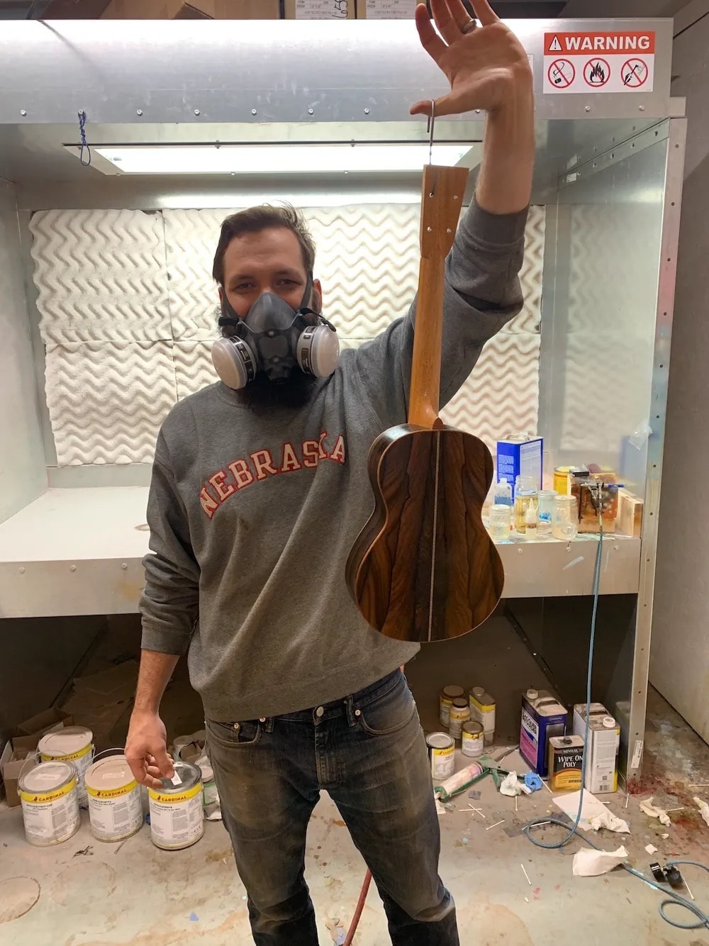 Micah wearing respirator holding a finished ukulele